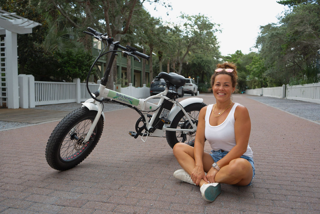 Rider sitting beside a Salty Spokes e-bike on a neighborhood street
